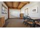 Living room area with wooden ceiling beams, table with chairs, and large window at 4880 Tall Horse Trl, Sedalia, CO 80135