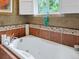 Bright bathroom featuring a large soaking tub with decorative tile surround and window at 109 Bear Creek Ln, Morrison, CO 80465