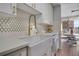 Bright kitchen featuring a white farmhouse sink, gold hardware, and a white and gold backsplash at 4800 E Hale Pkwy # 712N, Denver, CO 80220