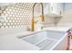 Close-up of a white farmhouse sink featuring modern white countertop and elegant gold hardware at 4800 E Hale Pkwy # 712N, Denver, CO 80220