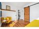 Cozy bedroom featuring hardwood floors, a sliding barn door, and an open doorway at 4455 Brentwood St, Wheat Ridge, CO 80033