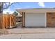 Spacious two car garage with large white door and wooden fence next to the brick house and small BBQ in the back at 3667 Hudson St, Denver, CO 80207