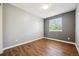 A bright bedroom with wood-look flooring and a large window overlooking the greenery outside at 9763 Cove Creek Dr, Highlands Ranch, CO 80129