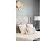 Close-up of a tufted headboard with neutral pillows and a bedside table with lamp at 9763 Cove Creek Dr, Highlands Ranch, CO 80129