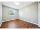 A bright bedroom with wood-look flooring and a large window overlooking the greenery outside at 9763 Cove Creek Dr, Highlands Ranch, CO 80129