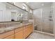 Bathroom with double sink vanity, granite counters, tile floors, and glass enclosed shower at 7770 Owl Creek Cir, Littleton, CO 80125