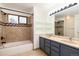 Bathroom showcasing a tiled shower-tub combo, double sinks with vanity, and open storage for toiletries at 5294 S Espana St, Centennial, CO 80015