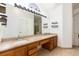Well-lit bathroom featuring double sinks, granite counters, vanity lighting, and gold trimmed shower at 5294 S Espana St, Centennial, CO 80015
