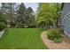 Expansive backyard featuring lush green lawn, mature trees, rock garden and a wooden deck, perfect for outdoor enjoyment at 2500 Lexington St, Lafayette, CO 80026