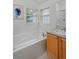 Bright bathroom showcasing a tiled tub with chrome fixtures, a window, and a wood cabinet sink at 2500 Lexington St, Lafayette, CO 80026