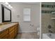 Well-lit bathroom featuring a vanity with a sink, a toilet, and a shower with decorative tile accents at 7084 Moss Ct, Arvada, CO 80007