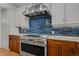 Close-up of the kitchen showcasing the stainless steel stove and hood against a blue-tiled backsplash at 7084 Moss Ct, Arvada, CO 80007