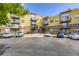 Exterior view of yellow apartment building with brick accents and ample parking for tenants and visitors at 9019 E Panorama Cir # D218, Englewood, CO 80112