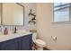 Stylish powder room features a blue vanity, modern wallpaper, floating shelves, and ample natural light at 15210 W Eastman Ave, Morrison, CO 80465
