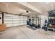 Spacious garage featuring an open concept, exercise equipment, storage shelving, and a large metal door at 68 S Moline St, Aurora, CO 80012