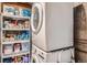 An organized laundry area features a stacked washer/dryer and shelving stocked with cleaning supplies at 68 S Moline St, Aurora, CO 80012