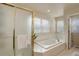 Bright bathroom featuring a jetted tub, glass shower door, tile floors, and a window at 1150 W 127Th Ct, Denver, CO 80234