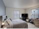 Neutral bedroom featuring a bed, hardwood floors, two windows, and dresser with a television at 1150 W 127Th Ct, Denver, CO 80234