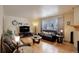 Inviting living room with hardwood floors, comfortable leather seating, and a large window overlooking a snowy scene at 1150 W 127Th Ct, Denver, CO 80234