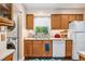 Well-lit kitchen featuring wood cabinets, a double sink with a window view, and appliances, and the in-unit laundry is right there! at 3485 S Forest St, Denver, CO 80222