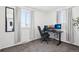 This office features two windows for natural light, gray carpet, and an ergonomic chair at 214 N 10Th Ave, Brighton, CO 80601