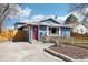 Charming blue home featuring a vibrant red door, picket fence, and well-maintained front yard at 214 N 10Th Ave, Brighton, CO 80601