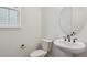 Modern half bathroom with a pedestal sink, round mirror, and black fixtures at 8230 Snake River St, Littleton, CO 80125