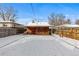 Large, snowy backyard features a covered patio, grill, and wooden fence at 4518 Vallejo St, Denver, CO 80211