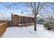 Quaint brick home with a charming front porch surrounded by a snow-covered yard at 4518 Vallejo St, Denver, CO 80211