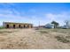 View of a large horse barn and smaller outbuilding sitting on a level dirt lot with a bright blue sky at 29881 E 128Th Ave, Commerce City, CO 80022