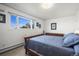 A bedroom with a large window, a wood dresser, and a queen-sized bed with blue comforter at 29881 E 128Th Ave, Commerce City, CO 80022