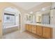 Bright bathroom featuring double vanity with wooden cabinets and soaking tub at 2660 Timberchase Trl, Highlands Ranch, CO 80126