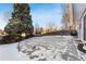 Large backyard patio area covered in snow, with tree and fence at 10401 W Lehigh Ave, Denver, CO 80235