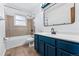 Bathroom with blue vanity, shower/tub combo and tiled walls at 10401 W Lehigh Ave, Denver, CO 80235