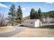View of the home's side and back exterior, nestled amongst mature pine trees at 10039 S Turkey Creek Rd, Morrison, CO 80465