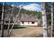 Cozy home featuring a brown roof, white siding, and wood deck in a tree-lined area at 10039 S Turkey Creek Rd, Morrison, CO 80465