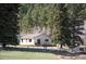 View of the home with mature trees, a cozy deck, and attractive landscaping in a serene wooded setting at 10039 S Turkey Creek Rd, Morrison, CO 80465