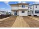 View of the back of a modern two-story home with light siding and a sliding glass door at 9297 Truckee Ct, Commerce City, CO 80022