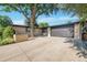Front exterior featuring brick, a black garage door, and a large tree at 7018 Reed Ct, Arvada, CO 80003