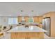 Bright open kitchen with an island, stainless steel appliances, and seamless access to the living area at 7018 Reed Ct, Arvada, CO 80003