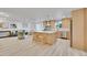 Open-concept kitchen featuring an island and light wood cabinets, seamlessly connected to the living area at 7018 Reed Ct, Arvada, CO 80003