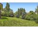 Lush green backyard with mature trees provides privacy and a serene outdoor space at 7863 W Friend Dr, Littleton, CO 80128