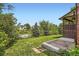 Expansive backyard with lush green grass, mature trees, and a view of neighboring homes at 7863 W Friend Dr, Littleton, CO 80128