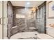 Modern shower with gray stone tile, built-in bench, and pebble floor in renovated bathroom at 7863 W Friend Dr, Littleton, CO 80128