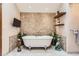 This bathroom showcases a soaking tub, a stone accent wall, lovely decor, and tiled floors at 7863 W Friend Dr, Littleton, CO 80128