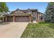 Two-story Tudor style home with a three car garage, brick accents, and well maintained lawn at 7863 W Friend Dr, Littleton, CO 80128
