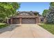 Tudor style two-story home with a three-car garage and brick accents on a large lot at 7863 W Friend Dr, Littleton, CO 80128