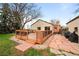 Spacious backyard featuring stone pavers, wooden deck, and lush green grass at 435 Balsam St, Lakewood, CO 80226