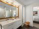 Bright bathroom with dual sink vanity, wood-framed mirror, and glass shower with tiled walls at 4432 Umatilla St, Denver, CO 80211