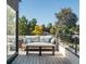 Stylish deck features a comfortable couch, a wooden coffee table, and green trees in the background at 4432 Umatilla St, Denver, CO 80211